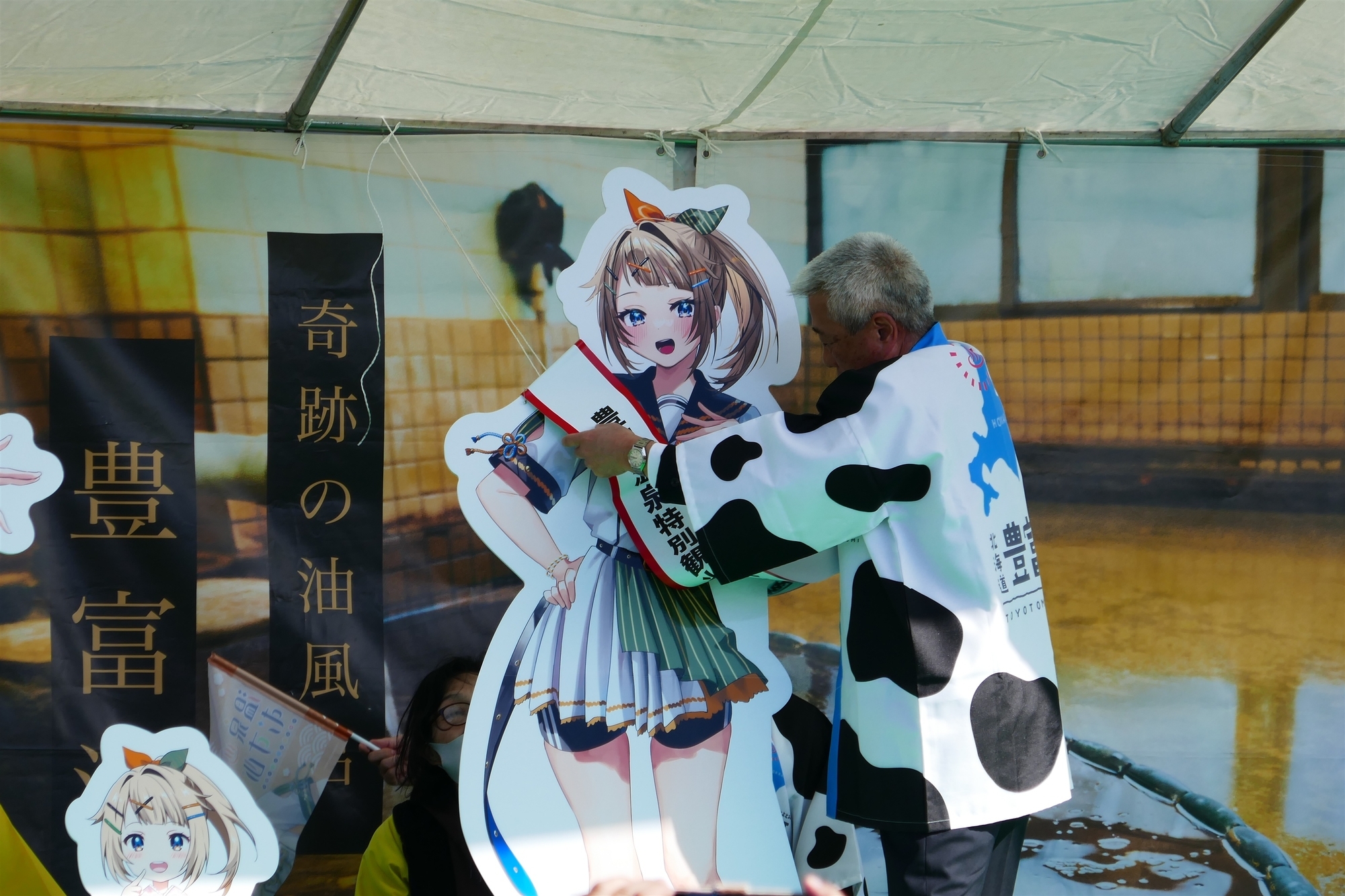 水由ちゃんパネルにタスキをかける豊富町長